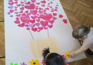 Dzieci przyklejające kwiatki i serduszka do dekoracji