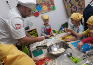 Dzieci wraz z kucharzem obierają warzywa