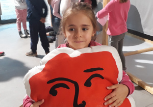 Dziewczynka trzymająca w rękach poduszkę w kształcie Polski