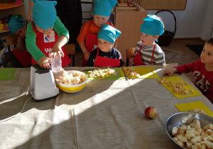 Dzieci trą jabłka na tarce elektrycznej