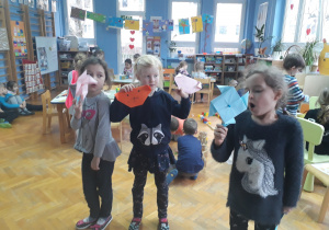 Dziewczynki pokazujące wykonane przez siebie zabawki papierowe