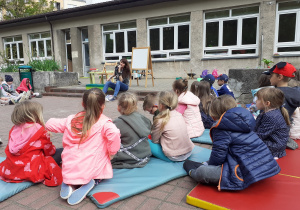 Dzieci słuchają książki czytanej przez Panią Olę w ogrodzie