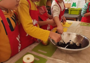 Dzieci nadziewają wydrążone jabłka żurawiną
